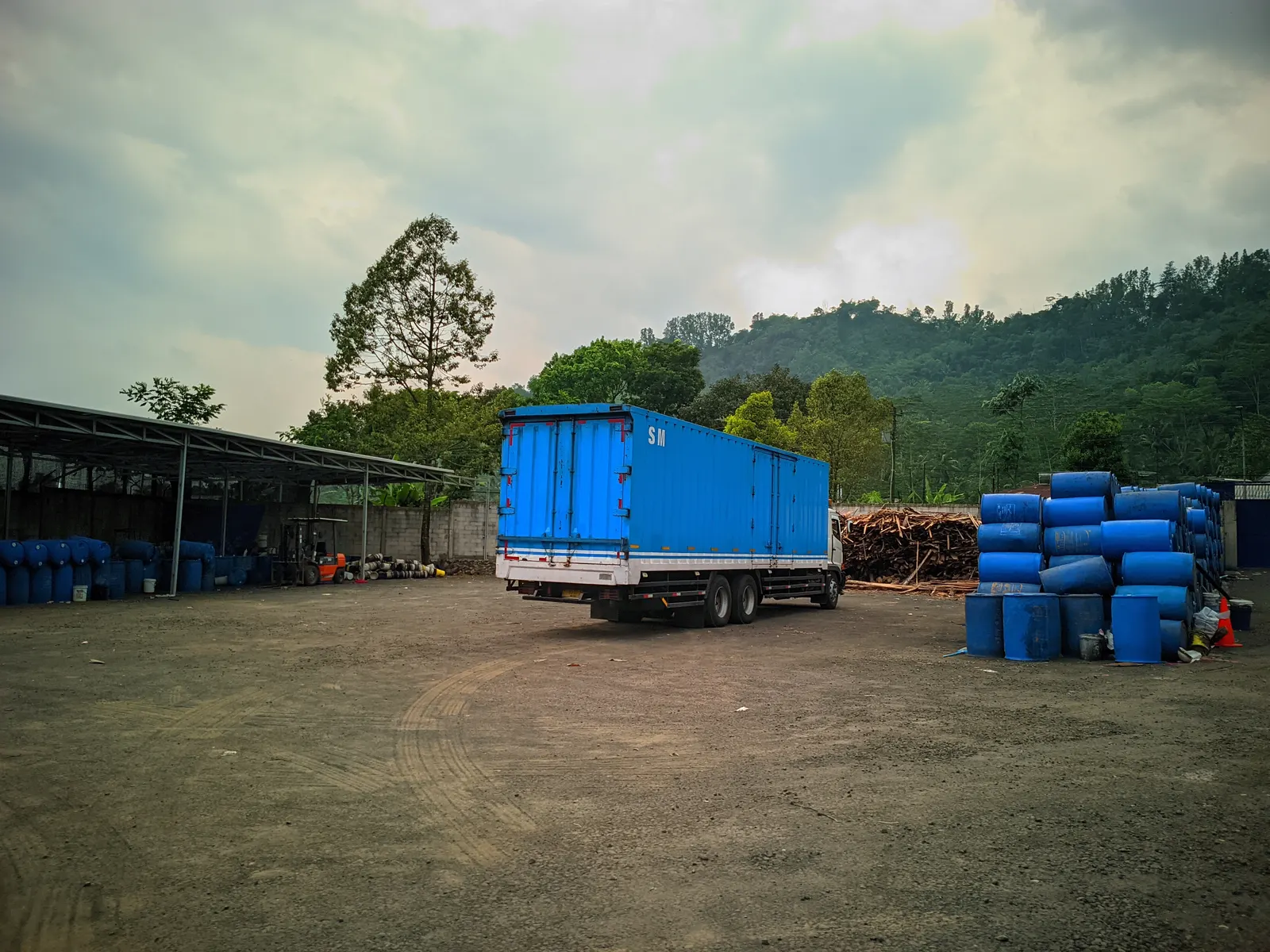 Halaman gudang dengan drum nira dan kayu bakar